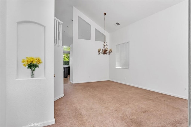carpeted empty room with a chandelier, high vaulted ceiling, visible vents, and baseboards