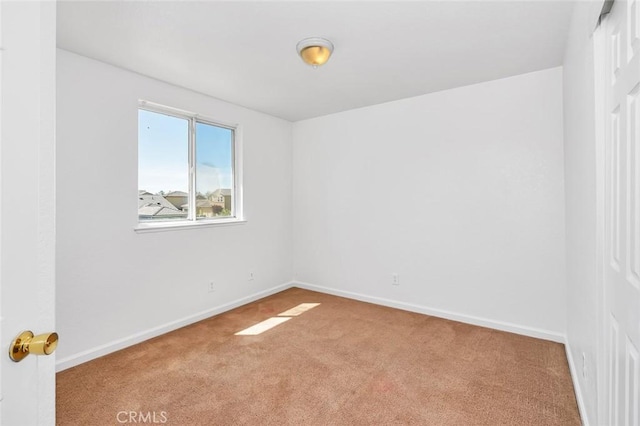 spare room featuring carpet and baseboards