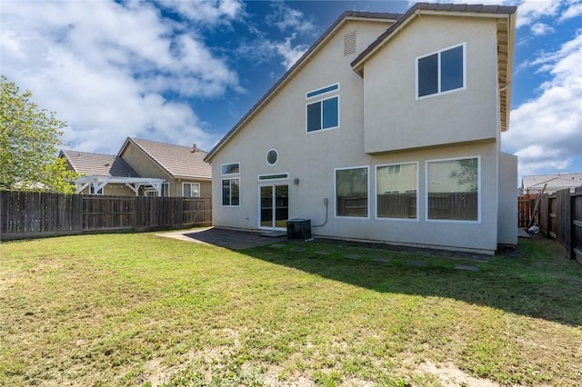 rear view of house featuring a yard, a fenced backyard, a patio, and stucco siding