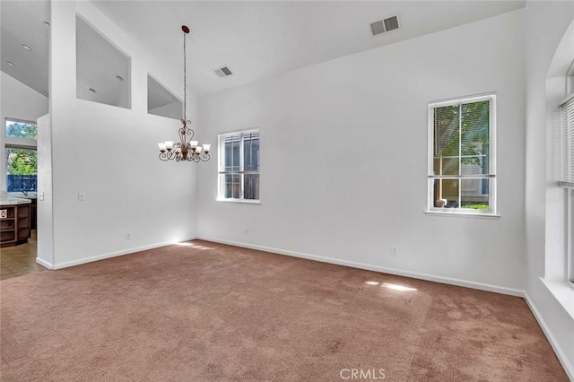 carpeted spare room featuring a chandelier, high vaulted ceiling, baseboards, and visible vents