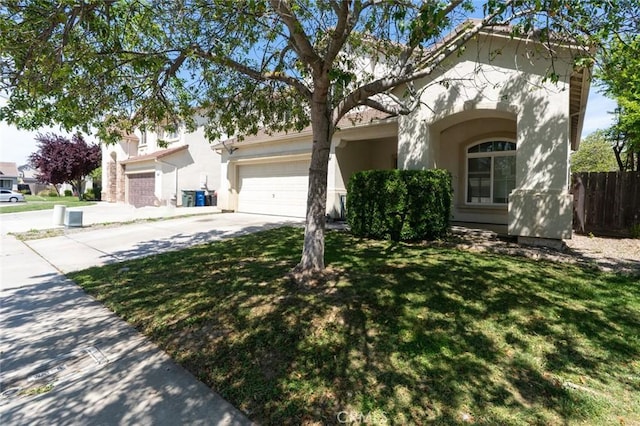 view of front facade with concrete driveway, stucco siding, a front lawn, a garage, and fence