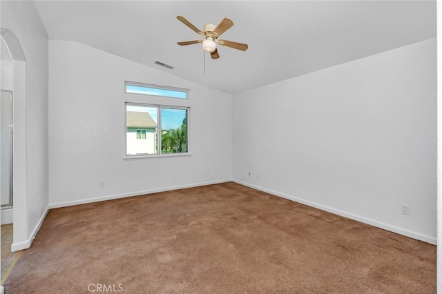 carpeted empty room with arched walkways, a ceiling fan, visible vents, lofted ceiling, and baseboards
