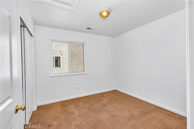unfurnished bedroom featuring a closet, baseboards, attic access, carpet floors, and visible vents