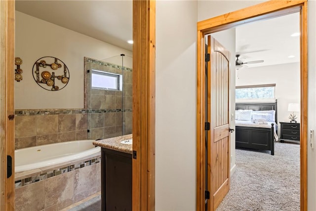 full bathroom featuring a ceiling fan, a relaxing tiled tub, and vanity