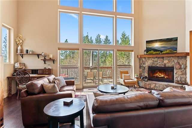 living area featuring a stone fireplace, hardwood / wood-style flooring, and a towering ceiling