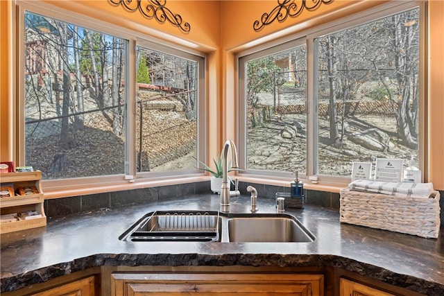 room details with brown cabinets, a sink, and dark countertops