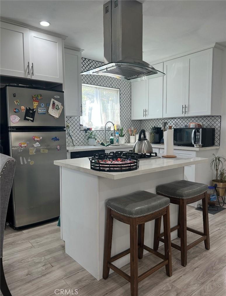 1715ST W 155th, Compton, CA 90220 - kitchen featuring freestanding refrigerator, exhaust hood, black microwave, backsplash, and light countertops