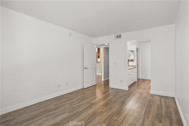 unfurnished bedroom featuring visible vents, baseboards, and wood finished floors