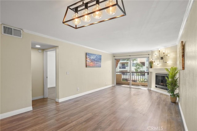 unfurnished living room featuring ornamental molding, visible vents, a chandelier, and wood finished floors