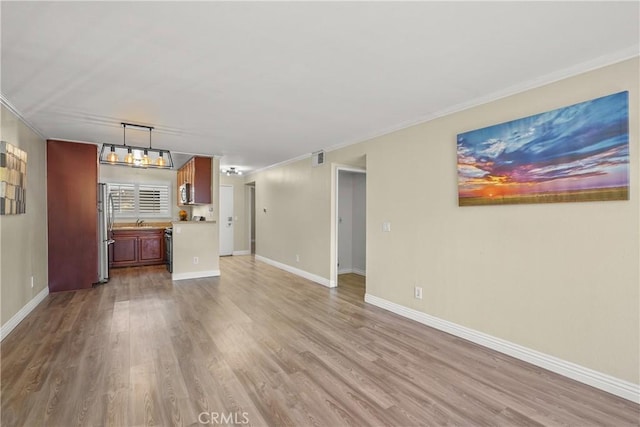 unfurnished living room featuring ornamental molding, baseboards, and wood finished floors