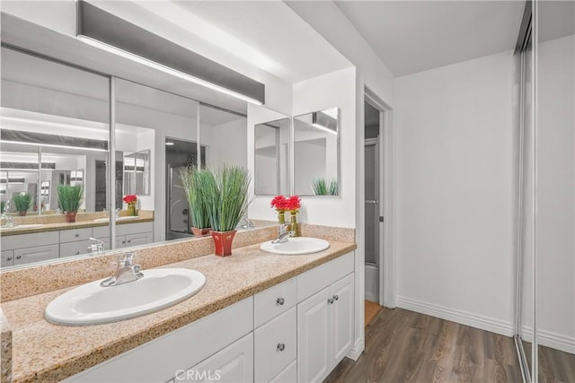 full bathroom with double vanity, a sink, and wood finished floors