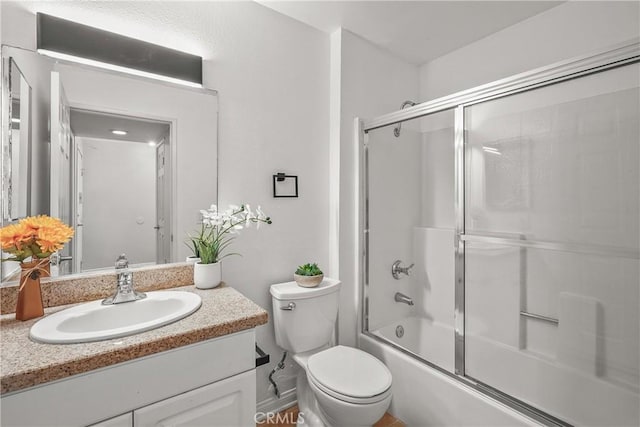 bathroom featuring combined bath / shower with glass door, vanity, and toilet