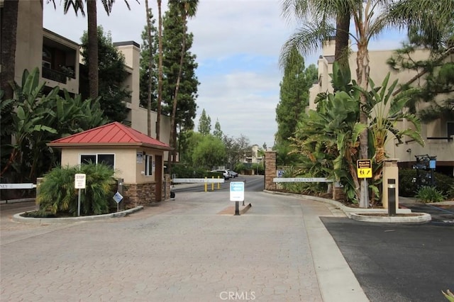 view of road with curbs, a gated entry, and traffic signs