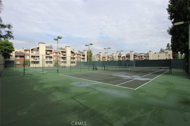 view of tennis court featuring fence and a residential view
