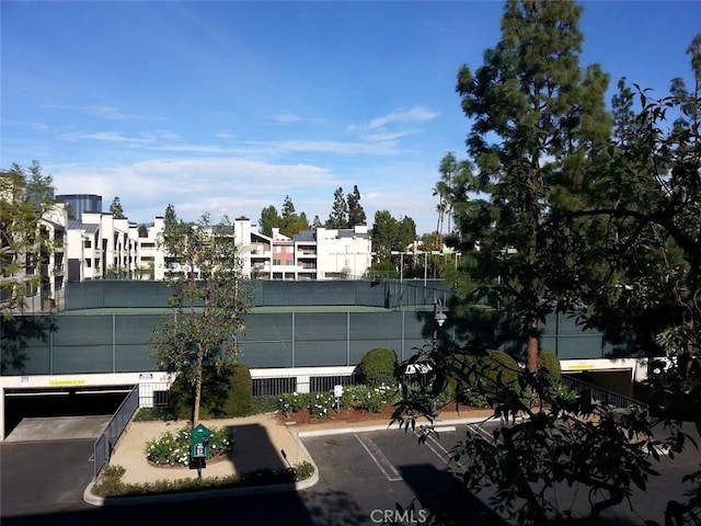 view of property's community with fence and uncovered parking