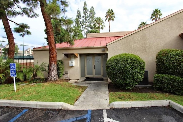 view of exterior entry with fence, metal roof, a standing seam roof, and stucco siding