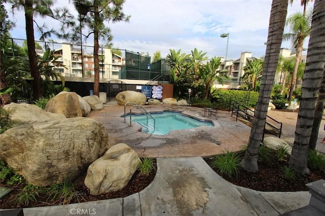 view of pool with a swimming pool, a patio area, a residential view, and fence