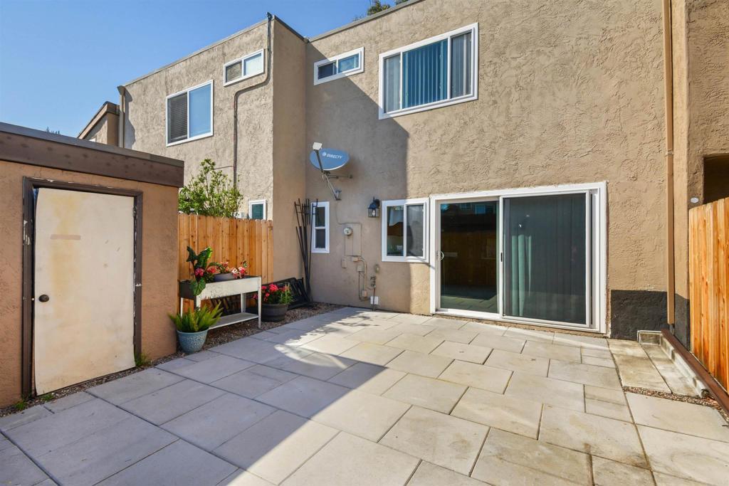 rear view of property featuring a patio area, fence, and stucco siding