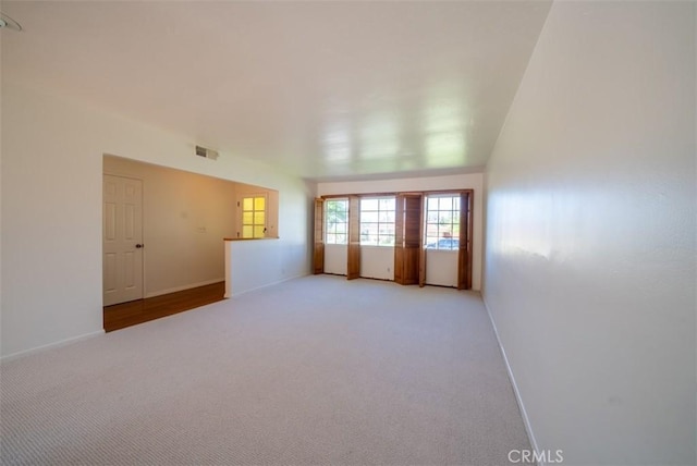 spare room featuring light colored carpet, baseboards, and visible vents
