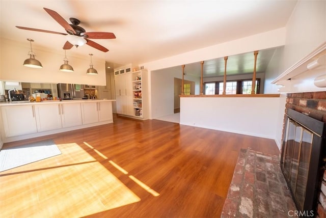 unfurnished living room with a ceiling fan, wood finished floors, and a fireplace