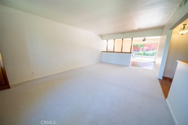 unfurnished living room featuring light carpet, baseboards, and a ceiling fan