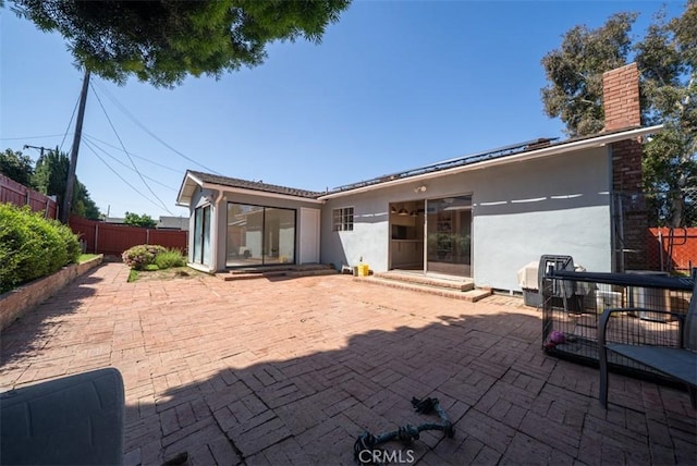back of property featuring a chimney, a patio area, stucco siding, and fence