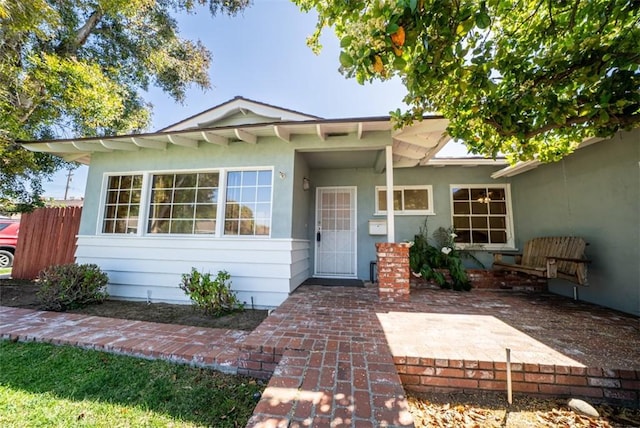 view of front of house featuring stucco siding and fence