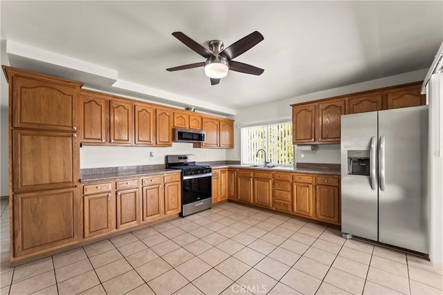 10806 Bayonne Dr, Riverside, CA 92505 - kitchen featuring appliances with stainless steel finishes, dark countertops, brown cabinets, ceiling fan, and a sink
