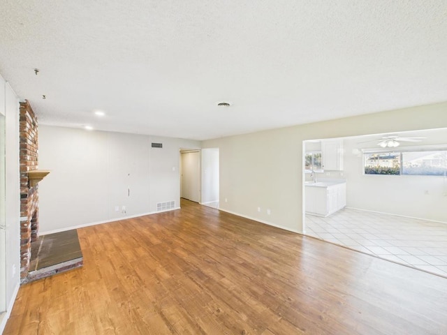 837 Oneonta St, Imperial Beach, CA 91932 - unfurnished living room with visible vents, light wood finished floors, a brick fireplace, and a ceiling fan