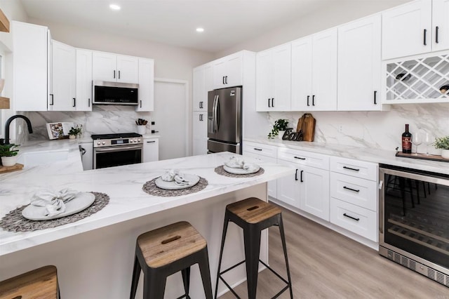 475 Parkwood Ln, Encinitas, CA 92024 - kitchen featuring appliances with stainless steel finishes, wine cooler, decorative backsplash, light stone countertops, and white cabinetry