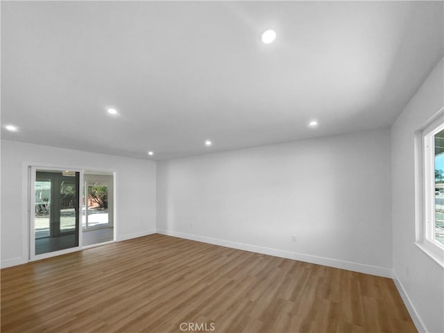 unfurnished room featuring wood finished floors, baseboards, and recessed lighting