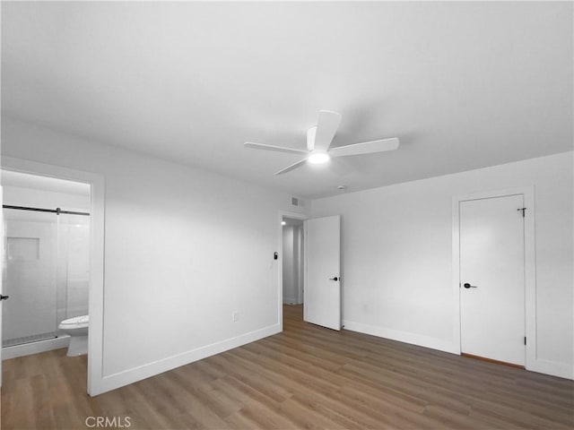 unfurnished bedroom with visible vents, baseboards, ensuite bathroom, a ceiling fan, and wood finished floors