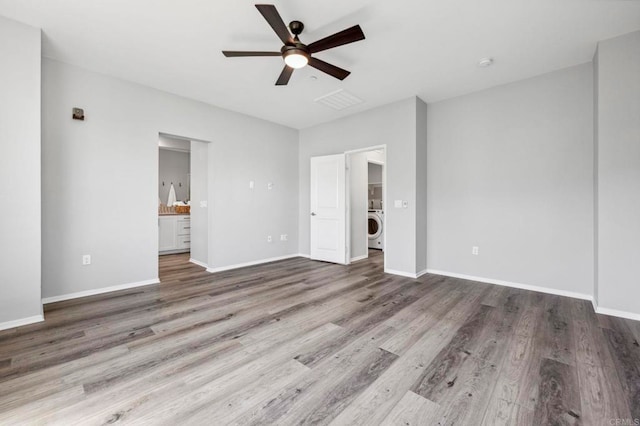 unfurnished bedroom with baseboards, washer / dryer, and wood finished floors