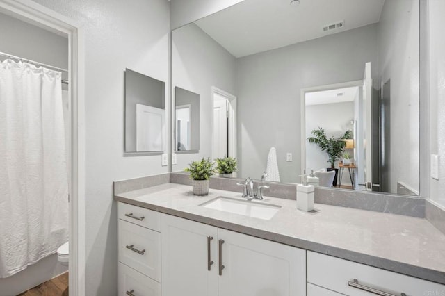 bathroom featuring a shower with shower curtain, vanity, toilet, visible vents, and wood finished floors