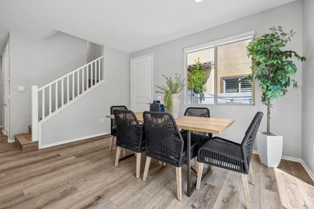 dining area with stairs, baseboards, and wood finished floors