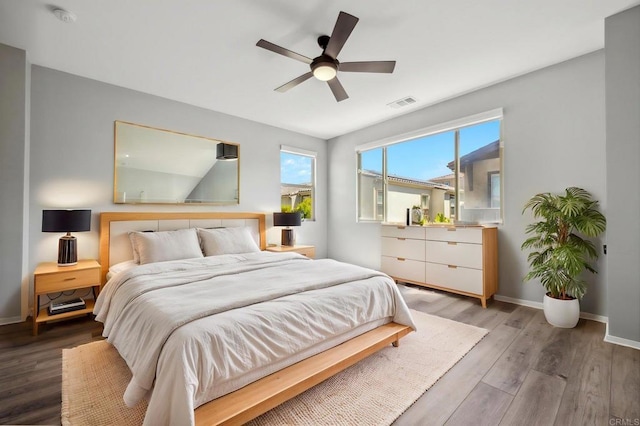 bedroom with visible vents, light wood-style flooring, a ceiling fan, and baseboards