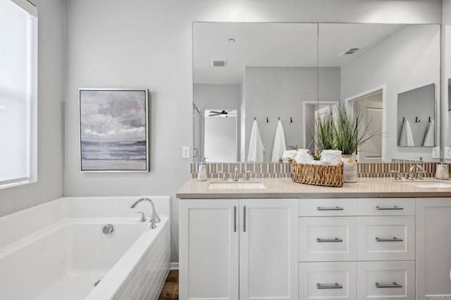 bathroom with a garden tub, double vanity, a sink, and visible vents