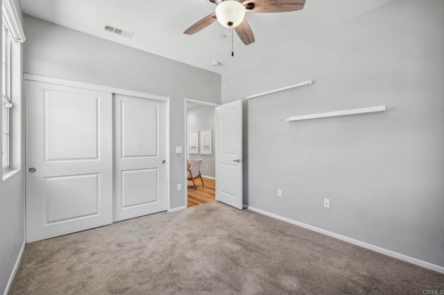unfurnished bedroom with a closet, baseboards, visible vents, ceiling fan, and carpet