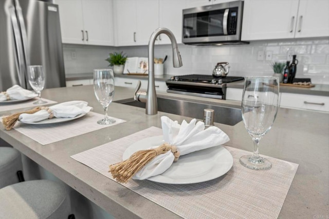 kitchen with tasteful backsplash, white cabinetry, and stainless steel appliances