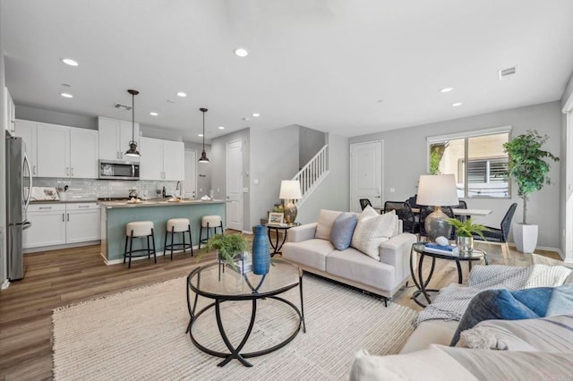 living area featuring baseboards, recessed lighting, stairs, light wood-style floors, and visible vents