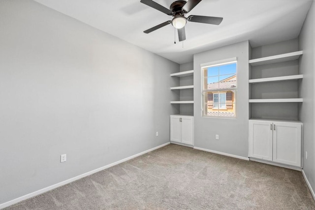 carpeted empty room featuring baseboards and a ceiling fan