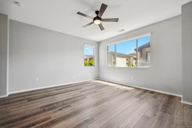 spare room featuring visible vents, ceiling fan, wood finished floors, and baseboards