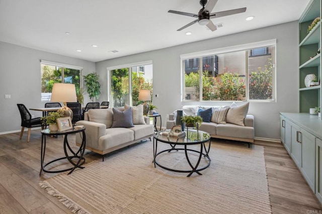 living area with light wood-style flooring, baseboards, and a ceiling fan