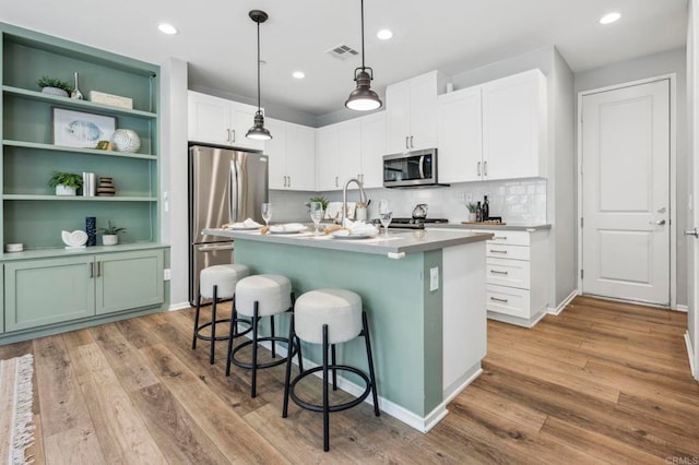 kitchen with visible vents, appliances with stainless steel finishes, a breakfast bar, and wood finished floors