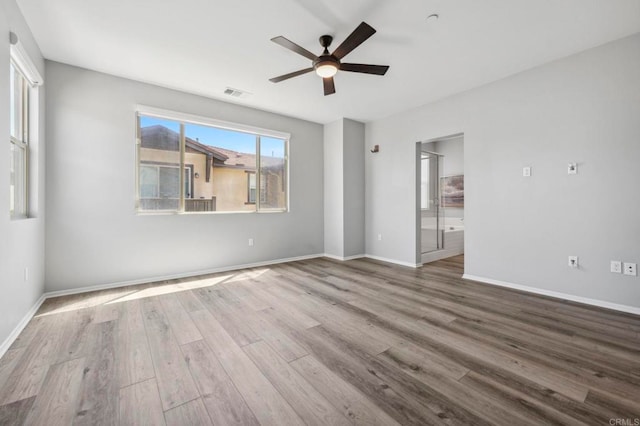 interior space featuring ceiling fan, ensuite bathroom, visible vents, wood finished floors, and baseboards