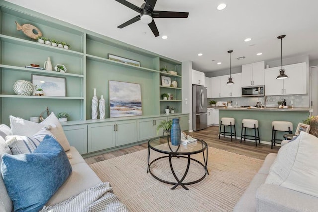 living area with visible vents, light wood-style flooring, a ceiling fan, and recessed lighting