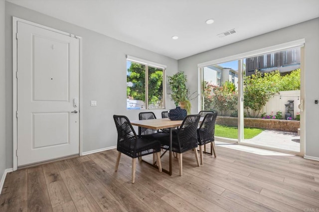 dining space with baseboards, light wood finished floors, and a healthy amount of sunlight