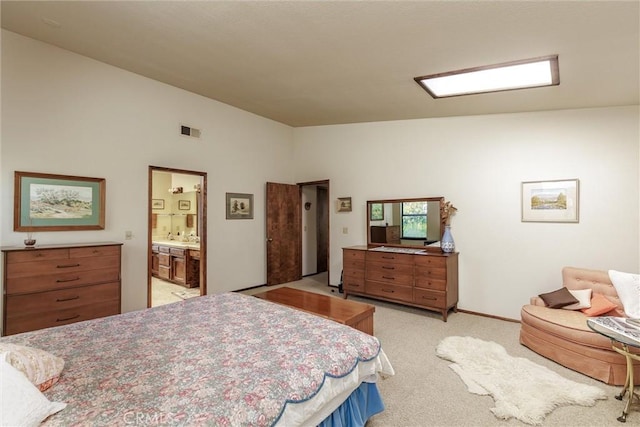 bedroom featuring ensuite bathroom, visible vents, and light colored carpet