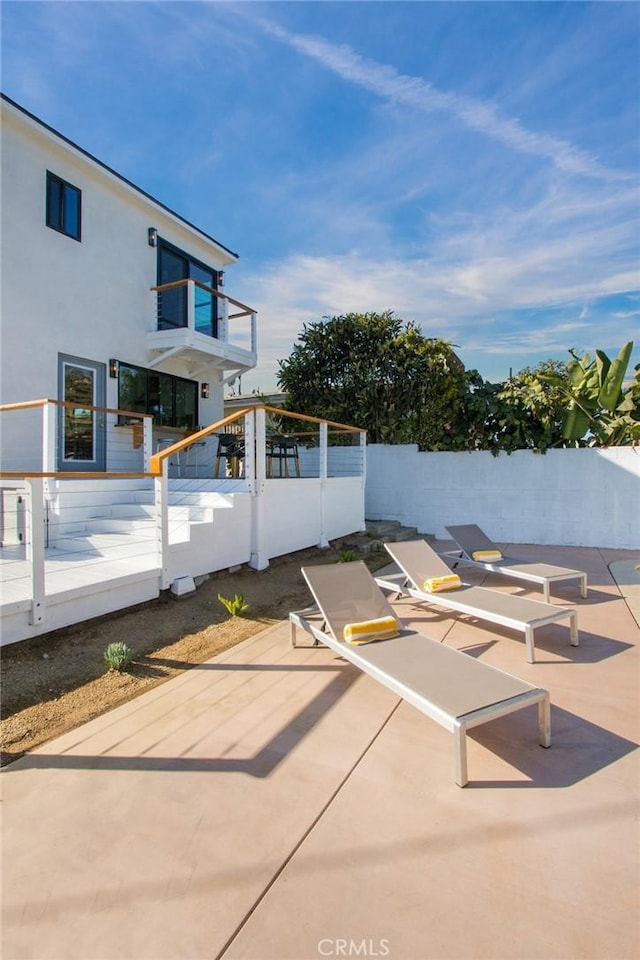 view of patio featuring fence and a balcony