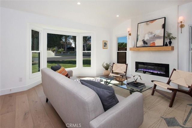 living room with a glass covered fireplace, recessed lighting, baseboards, and wood finished floors